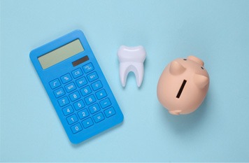 Calculator, prop tooth, and piggy bank on blue background