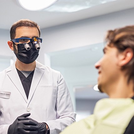 Man in black shirt smiling while sitting in dental chair