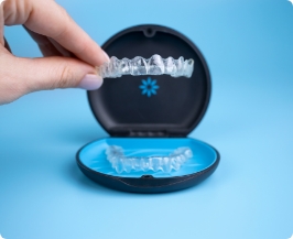 Hand placing an Invisalign clear aligner in its plastic case