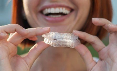 Dental patient holding Invisalign clear braces trays used for bite alignment