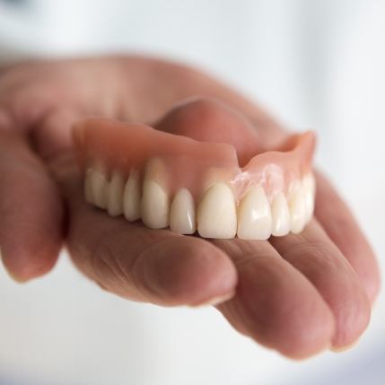 Hand holding a full denture