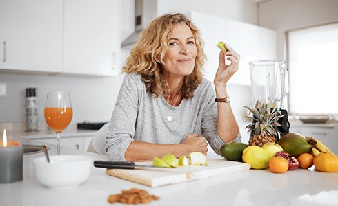 Woman smiling while preparing fruit in white kitchen