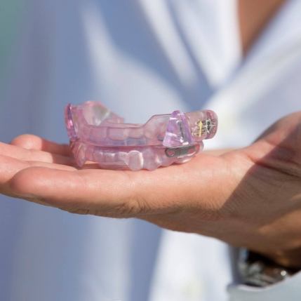 Hand holding a clear nightguard for bruxism