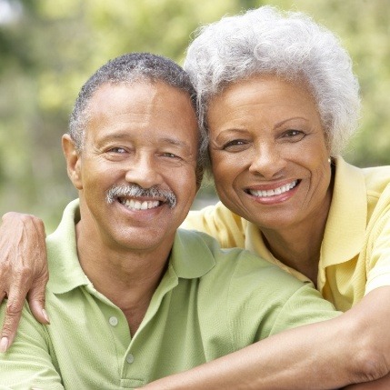 Man and woman smiling after full mouth restoration and rehabilitation