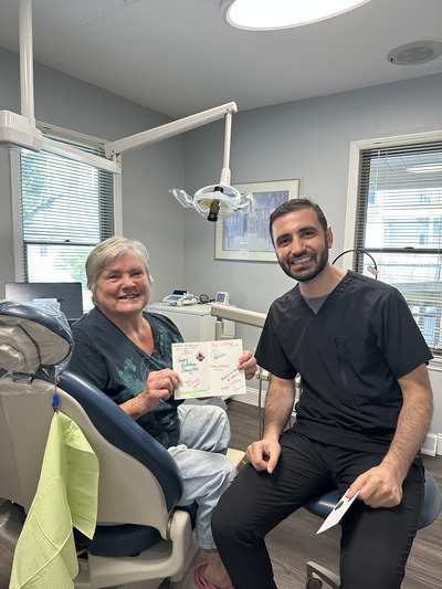 Dentist sitting next to a dental patient who is holding a certificate