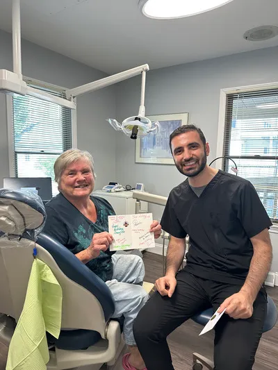Dentist sitting next to a dental patient who is holding a certificate