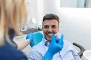 a dentist showing a patient how to use their Invisalign aligners