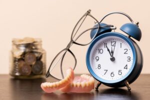 Dentures next to clock on nightstand 