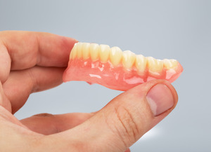 Holding dentures between finger and thumb