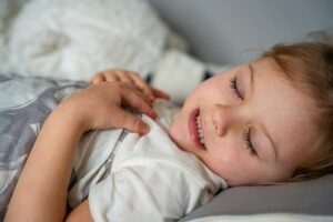 child asleep with their hands on their chest
